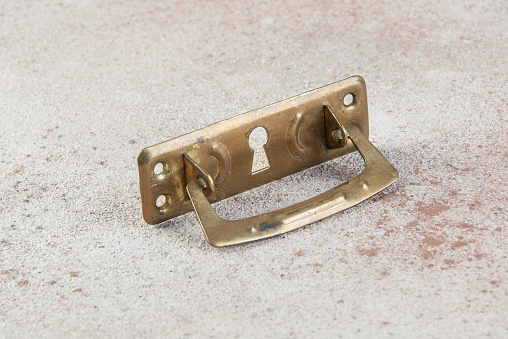 Old bronze furniture dresser handle on concrete background. Copy space for text.