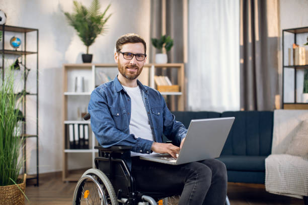 istock Young male freelancer sitting in wheelchair and using laptop 1323236085