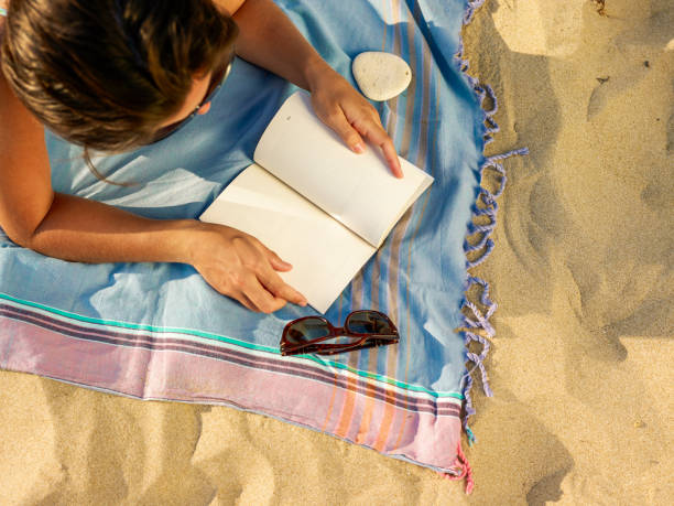 istock Woman on the beach reading a book 1323237335