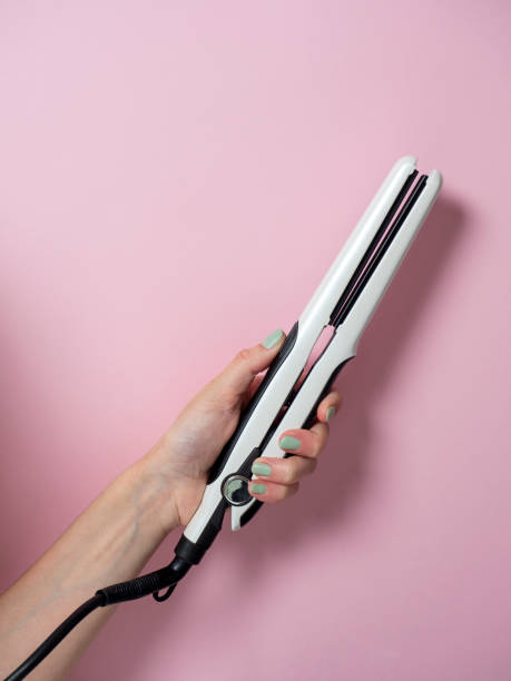 istock White curling iron in a woman's hand on a pnk background. An accessory for creating hairstyles. Beauty and fashion. Hair care. 1323237500