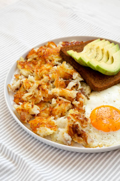 sabrosos hashbrowns fritos caseros y huevos en un plato, vista lateral. - hash brown gold food vegetable fotografías e imágenes de stock