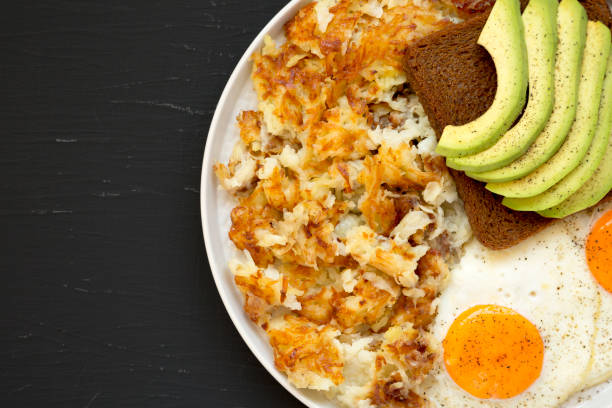 sabrosos hashbrowns fritos caseros y huevos en un plato sobre un fondo negro, vista superior. lay plana, arriba, desde arriba. espacio para texto. - hash brown gold food vegetable fotografías e imágenes de stock