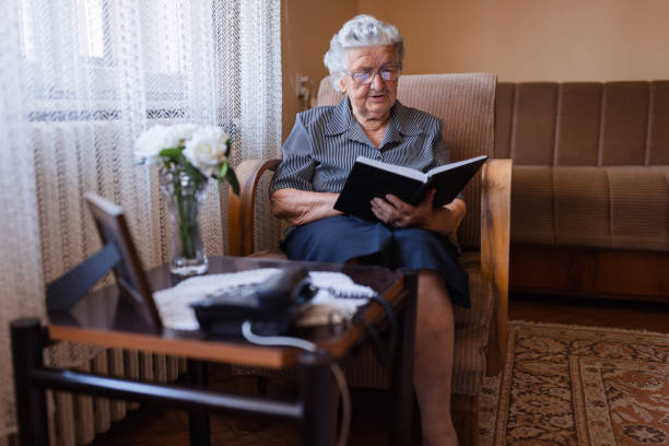 istock Serious old woman reading a book at home 1323239432