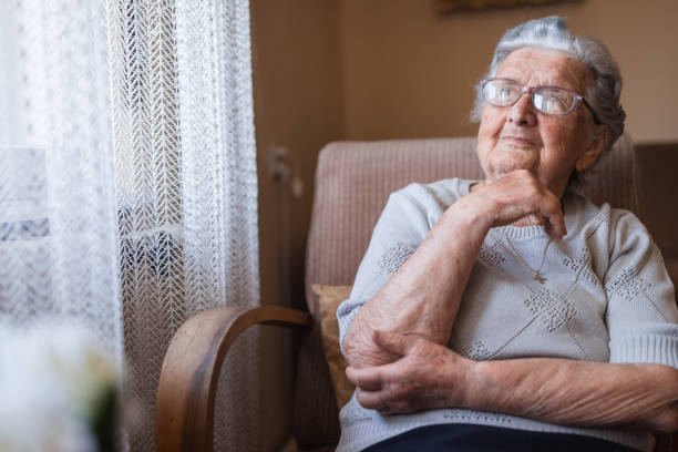 istock Senior woman smiling when looking through the window 1323239445