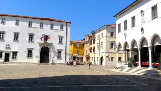 Slovenian Coast - Koper, stock photo Koper - Tito Square. A view of the main square in Koper with the old Loggia Palace and people walking on Titov Trg Square on a hot sunny day in summer. koper slovenia stock pictures, royalty-free photos & images