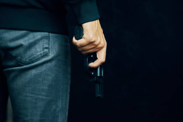 istock Man in dark clothing is holding gun. 1323245342