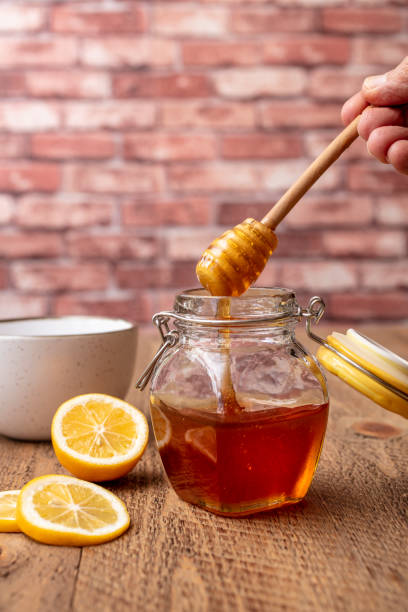 istock Honey dripping into the jar with lemon slices on a wood table top 1323250830