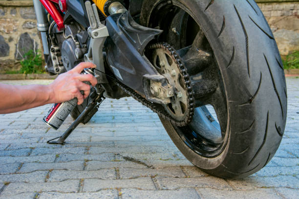 engrasar una cadena de motocicletas en primer plano - motorcycle engine brake wheel fotografías e imágenes de stock