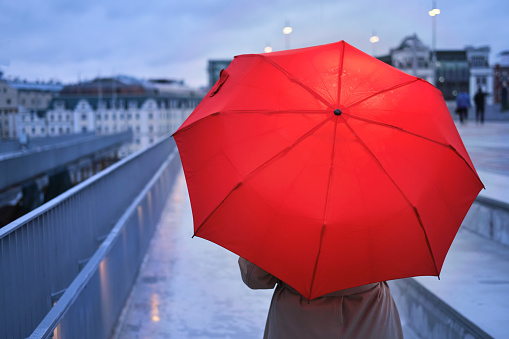 A woman with an umbrella in the rain on the background of city buildings