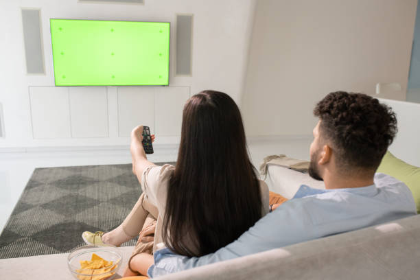 istock Young couple watching tv while relaxing on couch 1323260545