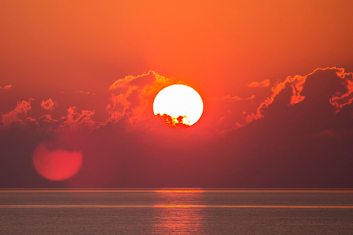 Deep orange sun over the ocean horizon.