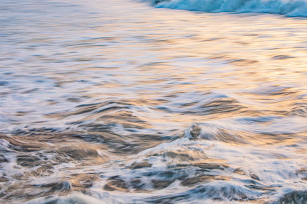 Rippled ocean surface and whitewash with gold light