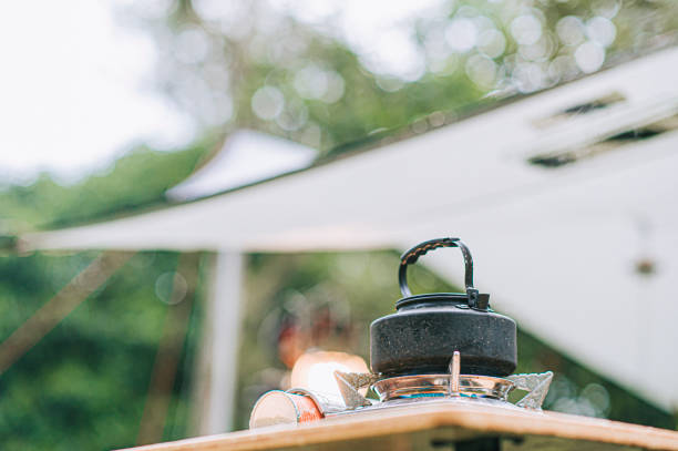 朝のピクニックテーブルで沸騰するキャンプストーブホットケトル - キャンプ　準備 ストックフォトと画像
