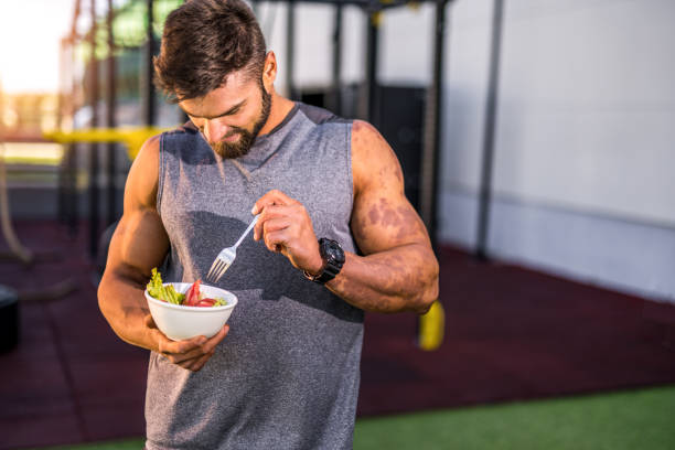 istock Happy young bodybuilder eating a vegetable salad. 1323270594