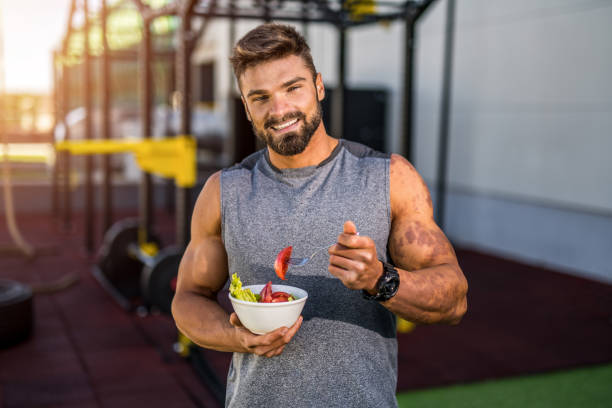 istock Happy young bodybuilder eating a vegetable salad. 1323270683