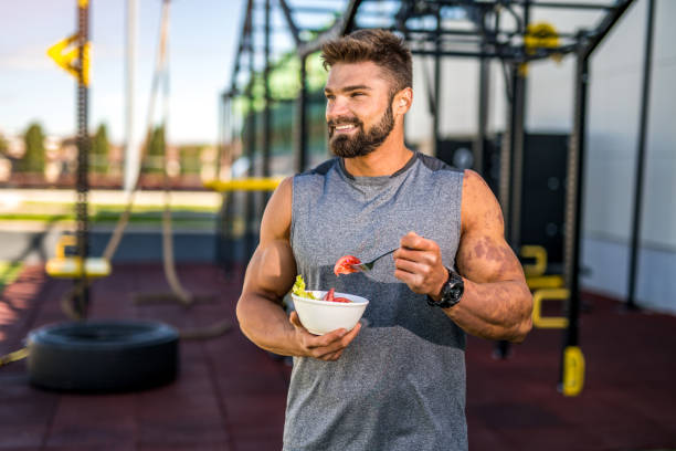 istock Happy young bodybuilder eating a vegetable salad. 1323271598