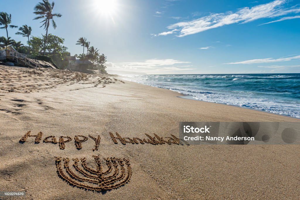 “Happy Hanukkah” written in the sand “Happy Hanukkah” written in the sand on the beach with a wave washing in Hanukkah Stock Photo