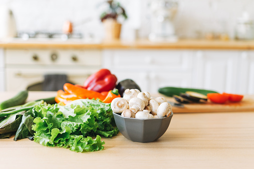 Ensalada verde de verduras frescas, pimientos, setas y berenjenas en la mesa de la cocina, proceso de cocción photo