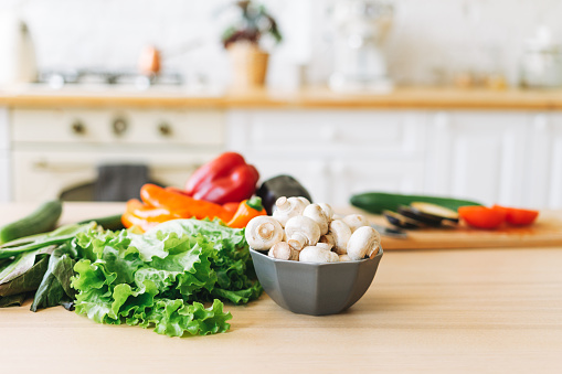 Fresh vegetables green salad, peppers, mushrooms and eggplant on kitchen table, cooking process