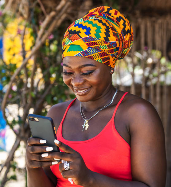 가나의 열대 마을에서 소셜 미디어에서 행복하게 채팅하는 아프리카 여성 - ghana 뉴스 사진 이미지