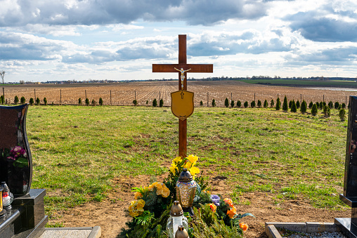 A wooden cross with a figure of Jesus with a nameplate without inscriptions, standing on a fresh earth tomb.