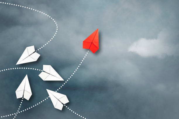 istock Red paper plane flying in a different direction than the white ones. Cloudy sky. Copy space. The concept of innovative solutions, creativity. Business. Lifestyle. 1323299997