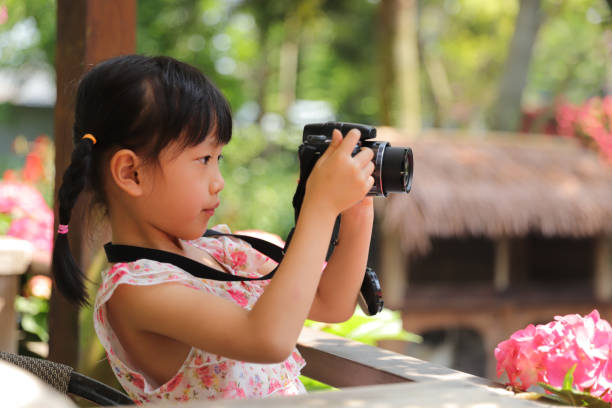 istock a Asian girl take photos with a digital camera. 1323301673