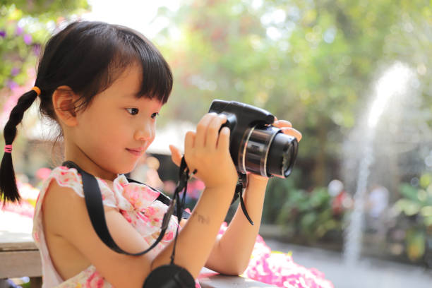 istock a Asian girl take photos with a digital camera. 1323301699