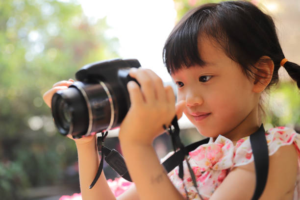 istock a Asian girl take photos with a digital camera. 1323301744