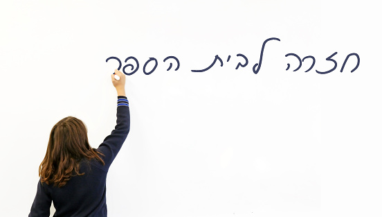An Israeli schoolgirl writing in Hebrew the saying: 