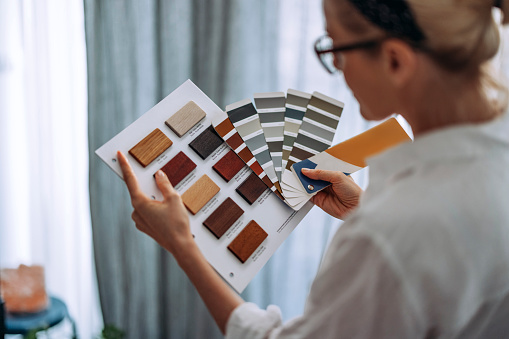 Cheerful architect holding colour catalogue and wooden samples choosing design palette for home interior