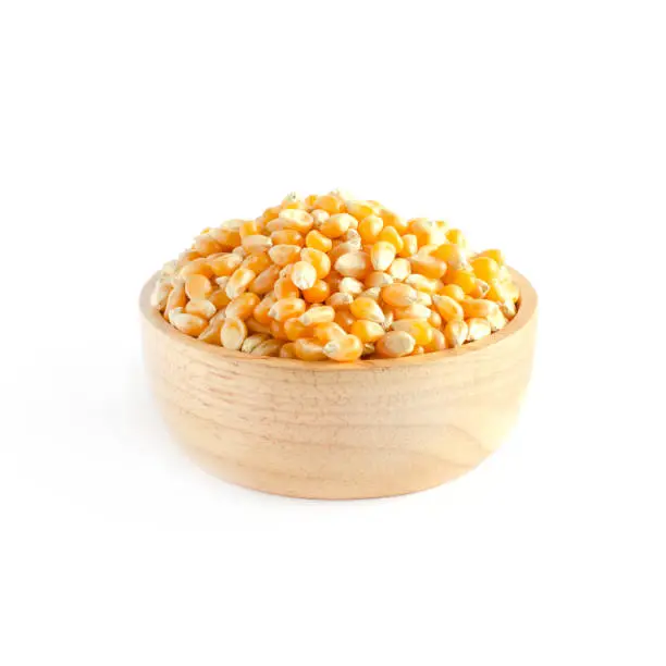 Photo of Dry organic corn seeds in wooden bowl on white background