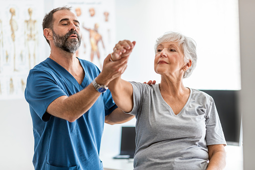 Shot of a Mature male physiotherapist assisting a senior female patient in recovery.