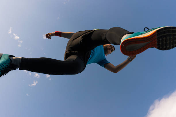 sportif court et saute dans le ciel - low angle view photos et images de collection