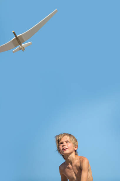 child with airplane playing over blue sky
