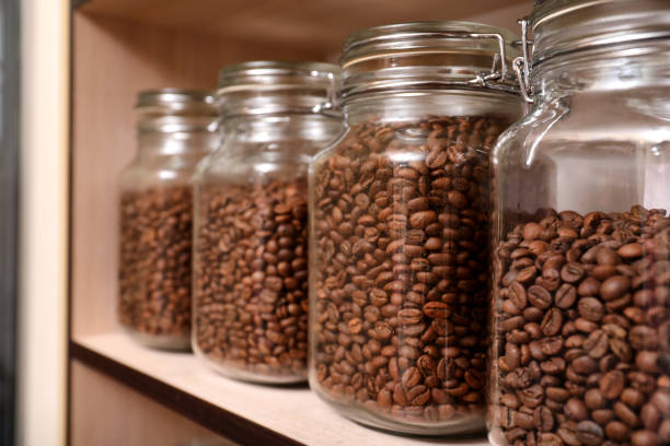 istock Glass jars with coffee beans on rack, space for text 1323307986