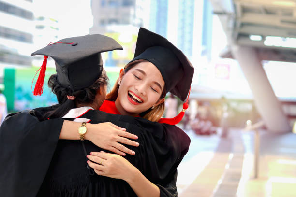 istock Two happy graduated women students with square academic hat cap hugging each other, people celebrating successful education and congratulating with friend on commencement graduation day when finished studies for university or college. 1323309199