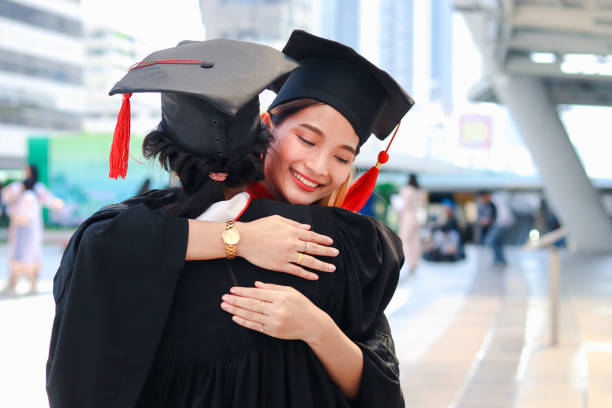 istock Two happy graduated women students with square academic hat cap hugging each other, people celebrating successful education and congratulating with friend on commencement graduation day when finished studies for university or college. 1323309207