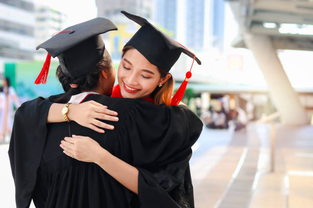 istock Two happy graduated women students with square academic hat cap hugging each other, people celebrating successful education and congratulating with friend on commencement graduation day when finished studies for university or college. 1323309219