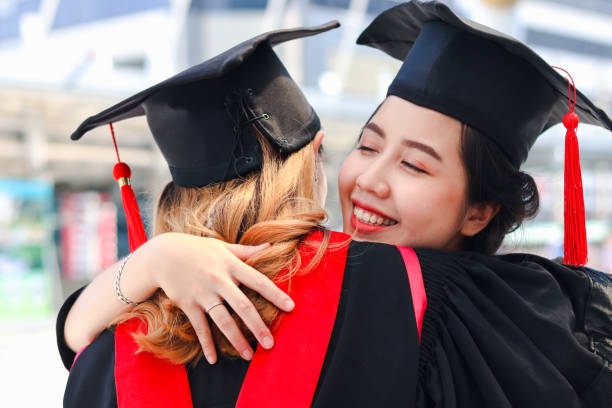istock Two happy graduated women students with square academic hat cap hugging each other, people celebrating successful education and congratulating with friend on commencement graduation day when finished studies for university or college. 1323309302