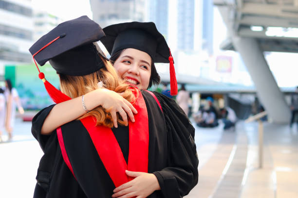 istock Two happy graduated women students with square academic hat cap hugging each other, people celebrating successful education and congratulating with friend on commencement graduation day when finished studies for university or college. 1323309344