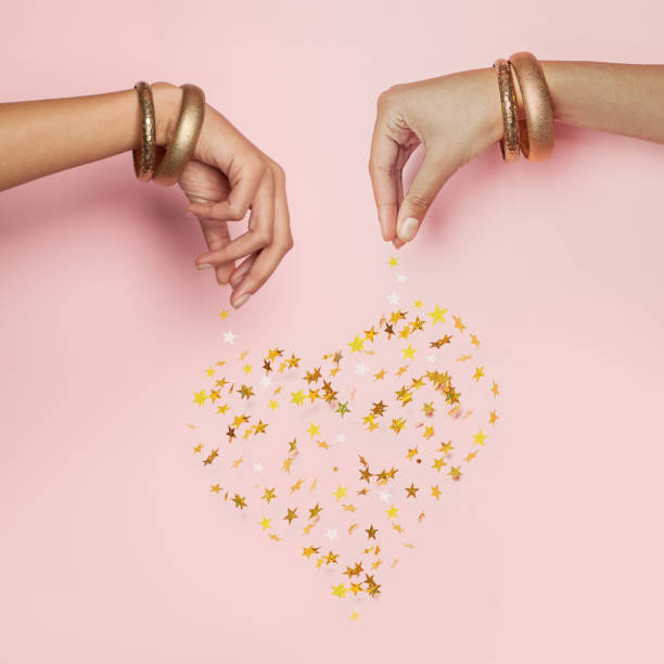 istock Female hands and falling confetti star. Heart on pink background 1323310050
