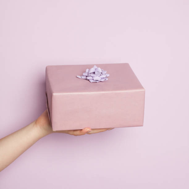 istock Pink minimal background composition with hand holding gift box 1323310181