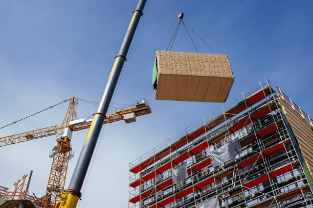 Crane lifting a prefabricated wooden building module to its position in the structure. Construction site of an office building in Berlin. The new structure will be built in modular timber construction. MODULAR WOODEN HOUSES made out of renewable resources. construction material stock pictures, royalty-free photos & images
