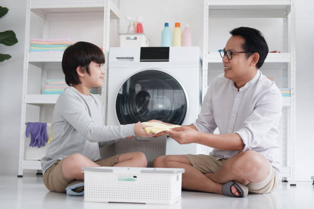 Smiling Asian father and little boy child is enjoying and Washing clothes together in Laundry room on holiday. Family activities and child educational for homeschool concept. Smiling Asian father and little boy child is enjoying and Washing clothes together in Laundry room on holiday. Family activities and child educational for homeschool concept. laundry husband housework men stock pictures, royalty-free photos & images