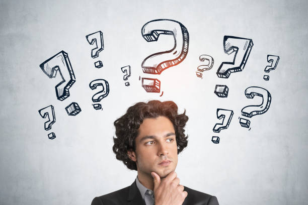 istock Businessman with thinking hand to chin, question marks sketch on concrete wall 1323313491