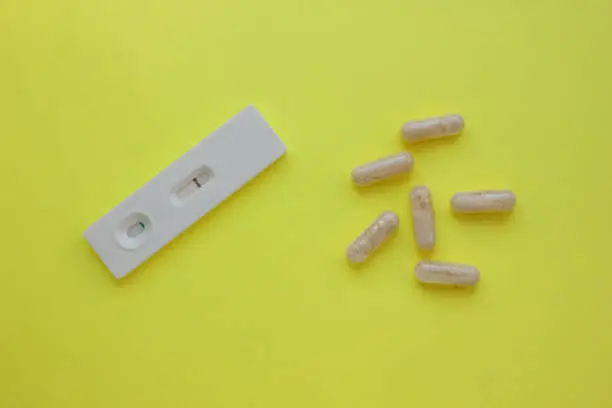 Photo of Negative pregnancy test and pills on a yellow background. Motherhood, children, pregnancy, concept of birth control. Health problems and problems with conception. abortion. contraception. Copy space.