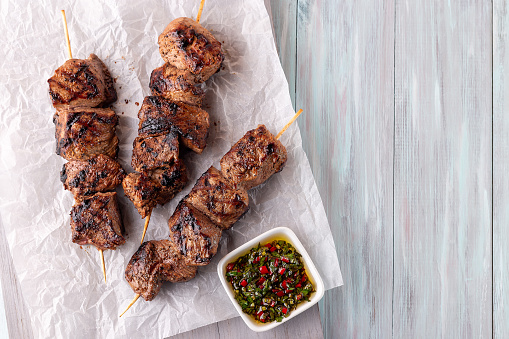 Grilled beef meat skewers with chimichurri sauce,  horizontal, top view, copy space