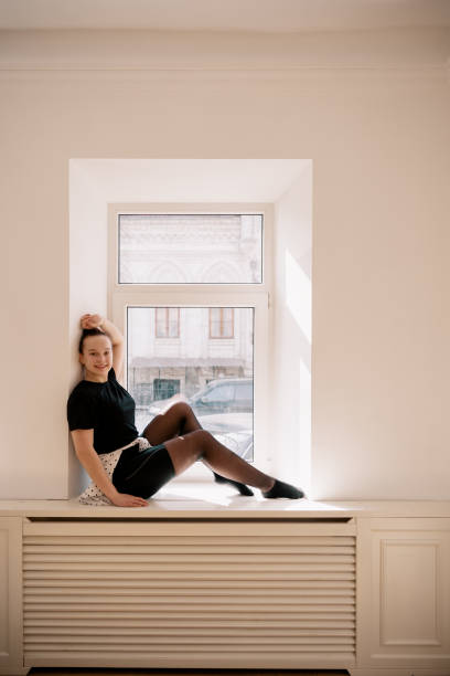 Cute teenager sitting near the window. Looking to camera, thinking