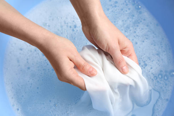 Top view of woman hand washing white clothing in suds, closeup Top view of woman hand washing white clothing in suds, closeup bleach stock pictures, royalty-free photos & images